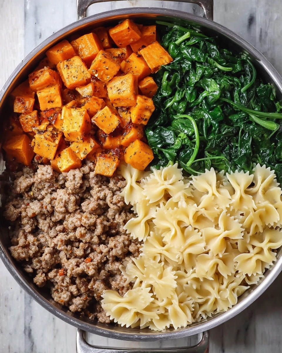 The dish in a metal pan shows four clear sections arranged side by side. The top left section has small, orange cubes of roasted sweet potatoes with a slightly crispy texture. On the top right, there is a pile of cooked spinach in dark green, with a soft and slightly shiny look. The bottom left section contains browned ground meat with a crumbly texture and bits of seasoning visible. On the bottom right, pale yellow bow-tie pasta fills the space with a smooth and firm texture. All the sections are neatly separated without mixing. The pan sits on a white marbled surface. photo taken with an iphone --ar 4:5 --v 7