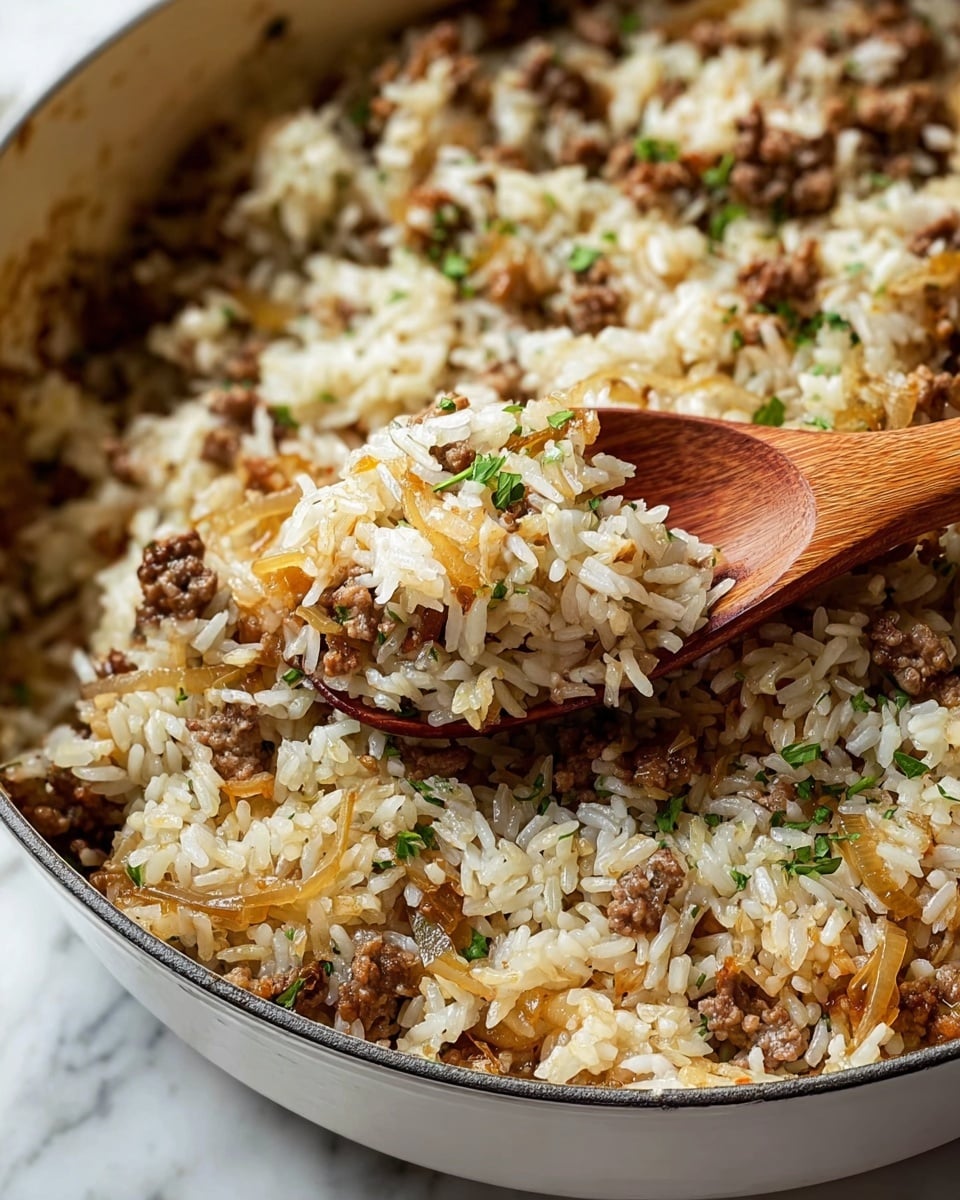 The image shows a close-up of a white cooking pot filled with a mixture of cooked white rice, small browned meat bits, and translucent cooked onions, all mixed evenly together. The texture of the rice is soft but separate, while the meat looks slightly crumbly and browned, giving a contrast of light and dark brown colors throughout the dish. Small green herb pieces are sprinkled on top, adding a touch of color. A wooden spoon is lifting a portion of the food from the pot, highlighting the grainy and mixed texture of the ingredients. The pot rests on a white marbled surface. Photo taken with an iphone --ar 4:5 --v 7