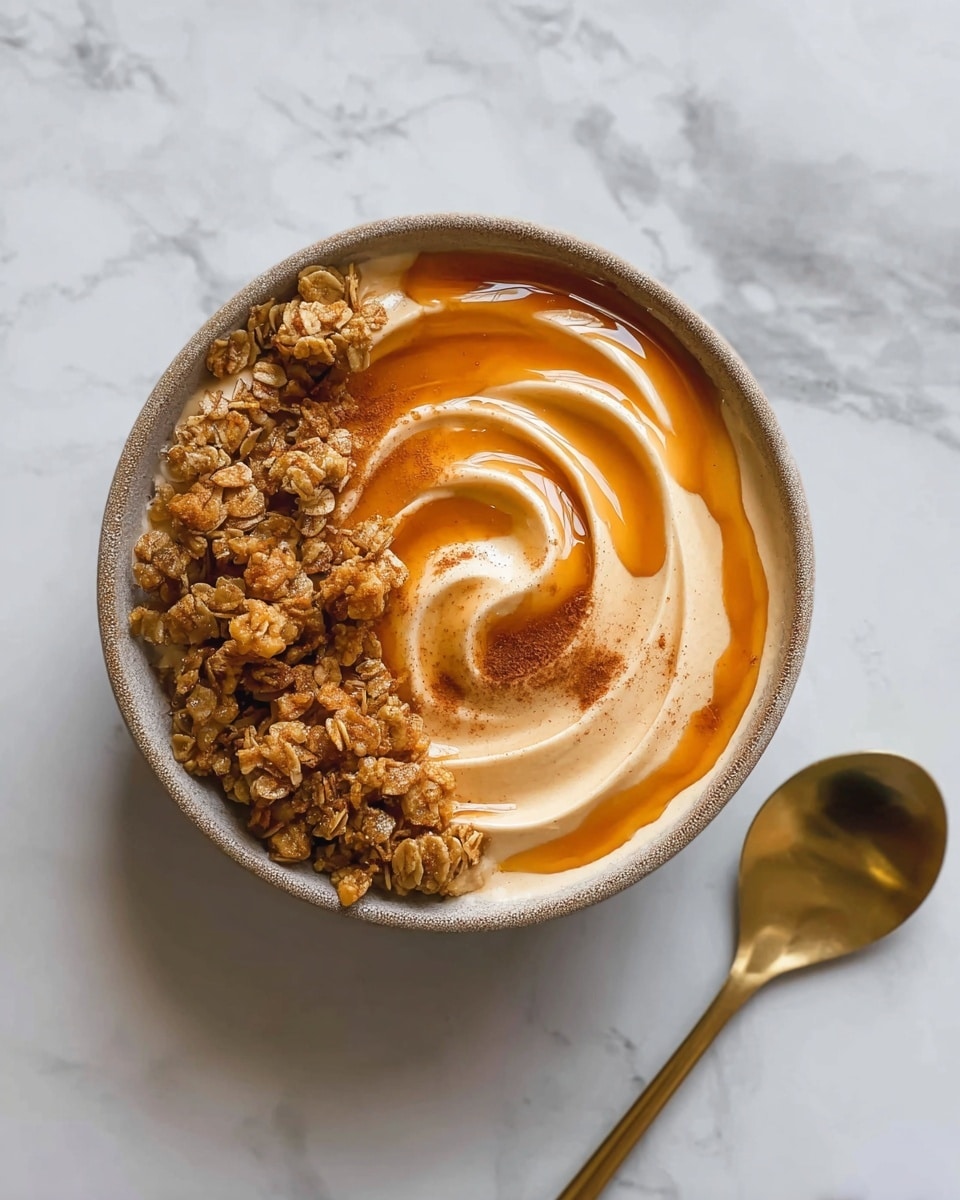 The image shows a white bowl filled with a smooth, thick layer of orange puree neatly swirled in the middle. On one side of the bowl, there is a layer of light brown rolled oats that look dry and slightly textured. On top of the puree, a thin drizzle of amber syrup glistens over the swirl, adding a shiny highlight. The bowl is set on a white marbled surface with gold streaks, and to the upper right side of the bowl, there is a shiny golden spoon placed flat. The whole scene gives a clean and warm feeling. photo taken with an iphone --ar 4:5 --v 7