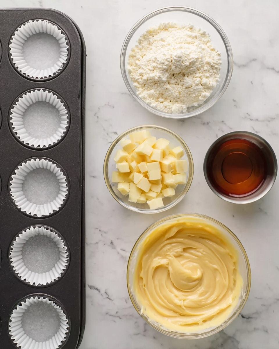 A flat view shows a black muffin tray with white paper liners arranged in a 3x4 grid on the left side, next to a white marbled surface holding four clear bowls. The top bowl holds a white powder mix with some clumps, the bottom bowl has small yellowish-white diced pieces, the large middle bowl contains a smooth, pale yellow batter with swirled texture, and a small metal cup to the right contains a dark amber liquid. photo taken with an iphone --ar 4:5 --v 7