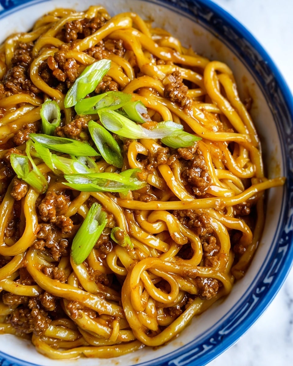 A close-up view of a bowl filled with thick noodles that are shiny and coated in a brown sauce, mixed with small pieces of cooked ground meat evenly spread throughout. On top, there are several slices of bright green scallions scattered around, adding contrast to the rich and saucy noodles. The bowl is white with a blue patterned rim, sitting on a white marbled surface, creating a fresh and clean background. photo taken with an iphone --ar 4:5 --v 7