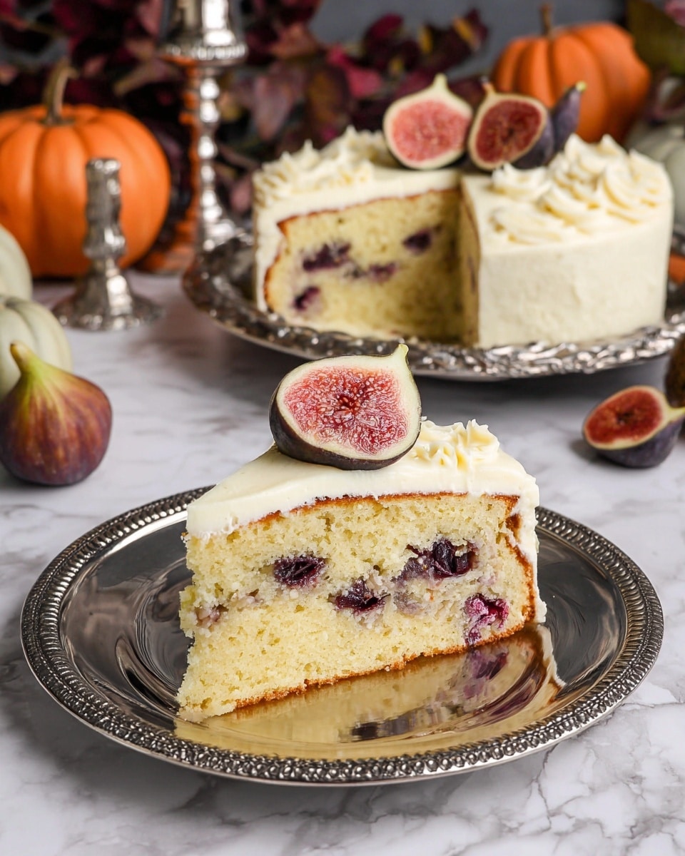 A slice of light yellow cake with dark purple fruit pieces inside sits on a shiny silver plate. The cake has one thick layer and is topped with a creamy layer of white frosting. On top of the frosting, there are two halved figs with dark purple skin and pinkish-red insides. Behind the slice, there is a whole cake with the same frosting and fig decoration, placed on an ornate silver tray. Small pumpkins and a silver candlestick are in the background on a white marbled surface. photo taken with an iphone --ar 4:5 --v 7