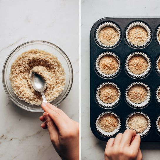 The image shows two parts side by side on a white marbled surface. On the left, a clear glass bowl is filled with a light brown crumbly mixture with a slightly rough texture, and a woman's hand is holding a silver spoon scooping some of the mixture. On the right, a black muffin tray with twelve white paper liners is shown, each liner partially filled with the same light brown crumbly mixture, and a woman's hand is pressing the mixture into one of the liners using a silver spoon. The overall colors are warm browns and whites with a clean kitchen feel photo taken with an iphone --ar 4:5 --v 7