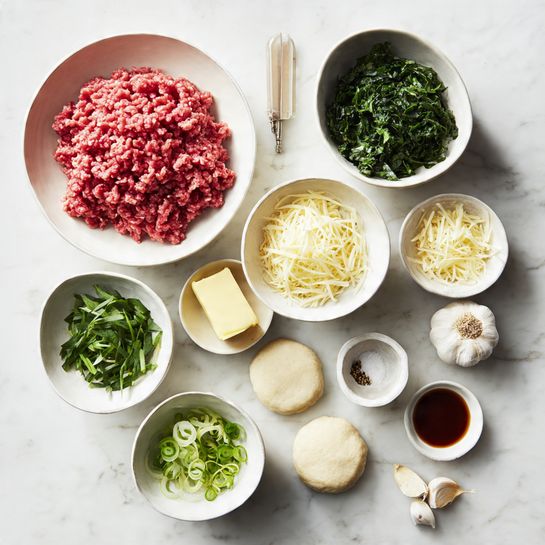 The image shows a white marbled surface with three round, light beige dough circles placed on the bottom right side. Above them, there are several white bowls and small dishes arranged neatly. One large white bowl contains bright red ground meat with a slightly coarse texture. Another large white bowl holds chopped dark green leafy herbs. Two smaller white bowls filled with shredded pale yellow cheese are placed near the center. A small bowl contains chopped light green scallions, while another has fresh green herbs. There is also a small white dish with a yellow chunk of butter, a tiny white bowl of minced light yellow garlic, a small dish with coarse salt, a tiny bowl holding a dark brown liquid with some seasoning on top, and two whole garlic cloves resting nearby. Photo taken with an iphone --ar 4:5 --v 7