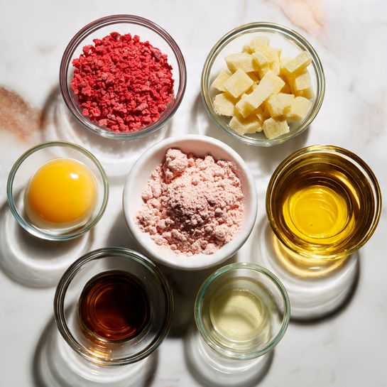 The image shows six small glass bowls arranged in a loose circle on a white marbled surface. In the center, there is a white bowl filled with pink powder that has a slightly rough, crumbly texture. Surrounding the bowl, the glass bowls each have different ingredients: top left holds bright red granules, top right contains pale yellow rectangular chunks, bottom left has a raw egg with a clear white and yellow yolk, bottom center holds dark brown liquid, and bottom right contains a light golden liquid. The colors and textures of each ingredient create a vibrant and neat arrangement. Photo taken with an iphone --ar 4:5 --v 7