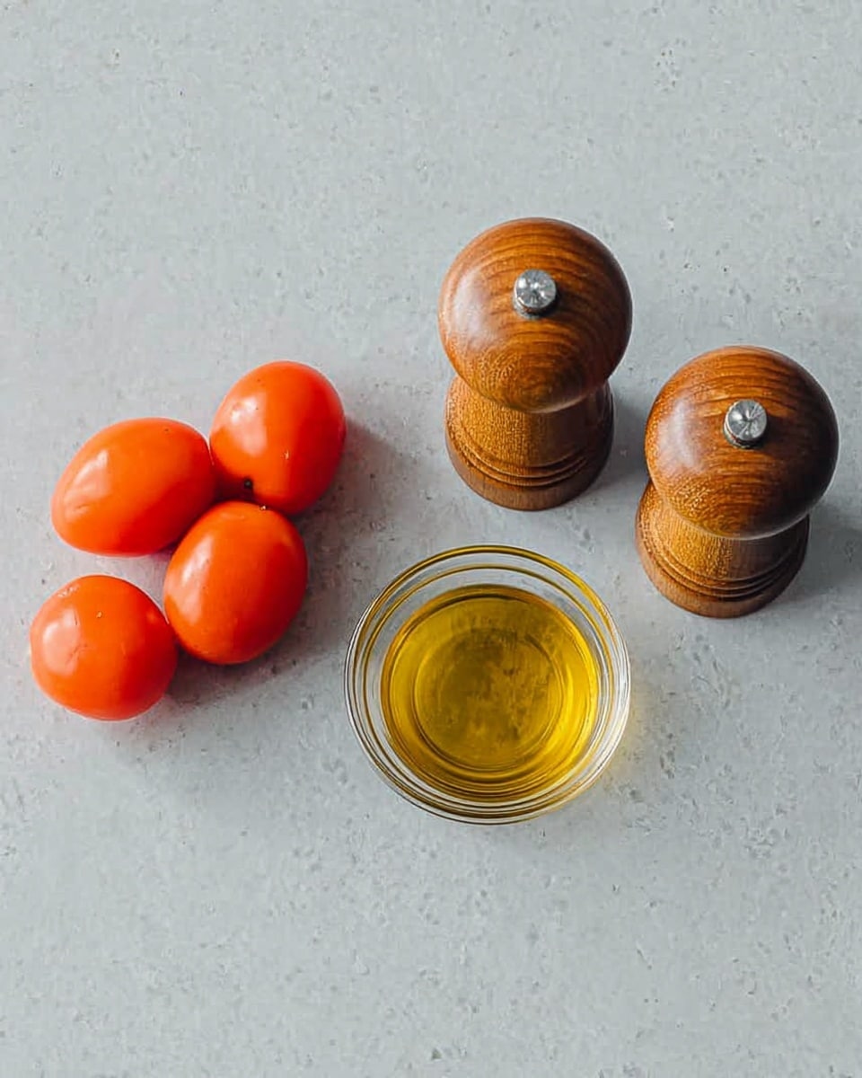 The image shows four small, smooth, reddish-orange tomatoes placed in a loose group on the left side of a shiny gray surface. Next to the tomatoes, there is a small clear glass bowl filled with golden olive oil. To the right of the bowl are two wooden pepper and salt grinders with a natural brown color and a slightly shiny finish. The background is a white marbled texture. photo taken with an iphone --ar 4:5 --v 7
