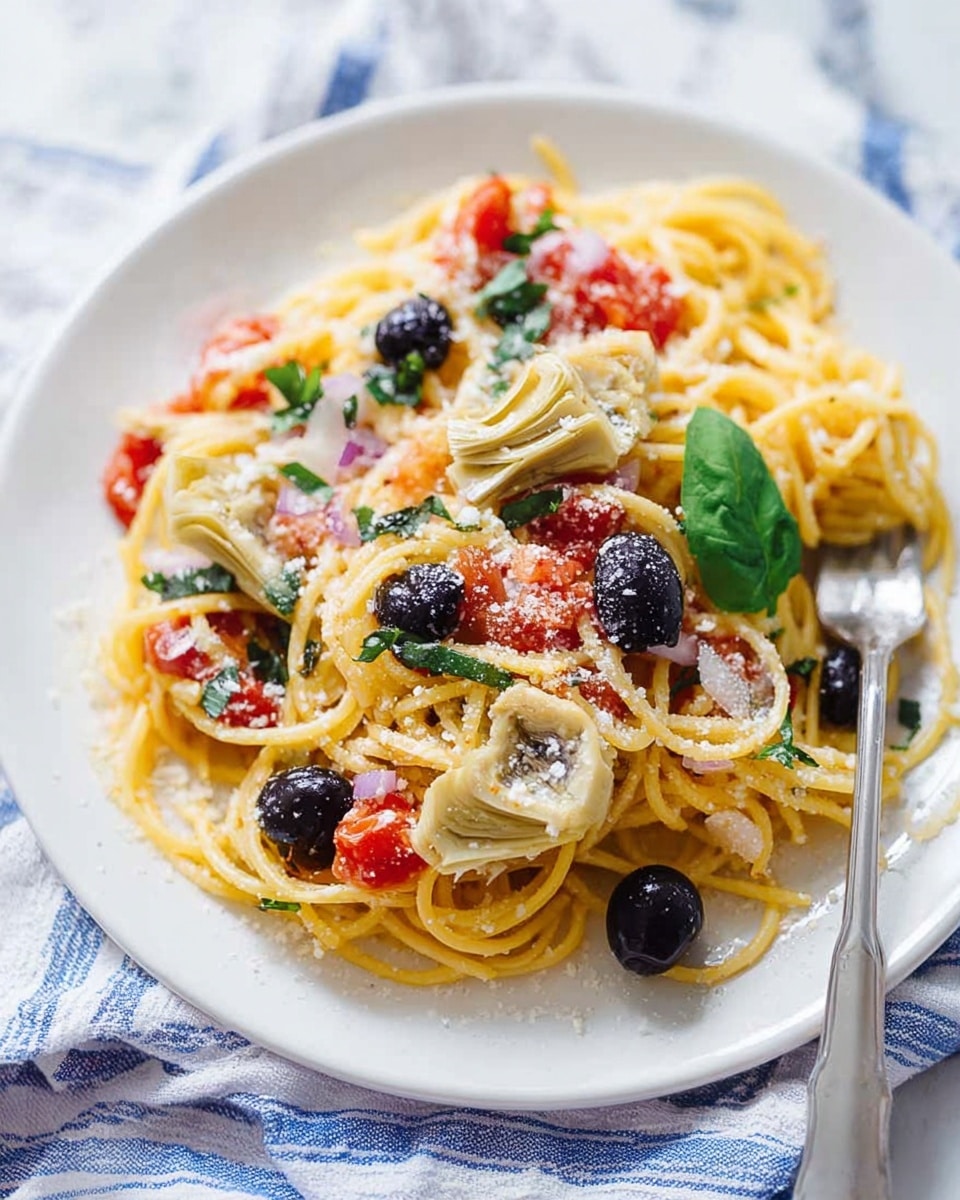 A white plate filled with a single layer of yellow spaghetti noodles topped with small pieces of red tomato and black whole olives scattered around. There are two light beige artichoke hearts placed near the edge of the plate, mixed with bits of finely chopped white onion and small green herb leaves. Fresh green basil leaves sit on top as garnish. The spaghetti is lightly dusted with grated white cheese. A silver fork rests on the right side of the plate, partially rubbing the noodles. The plate is set on a soft blue and white striped cloth over a white marbled surface. photo taken with an iphone --ar 4:5 --v 7