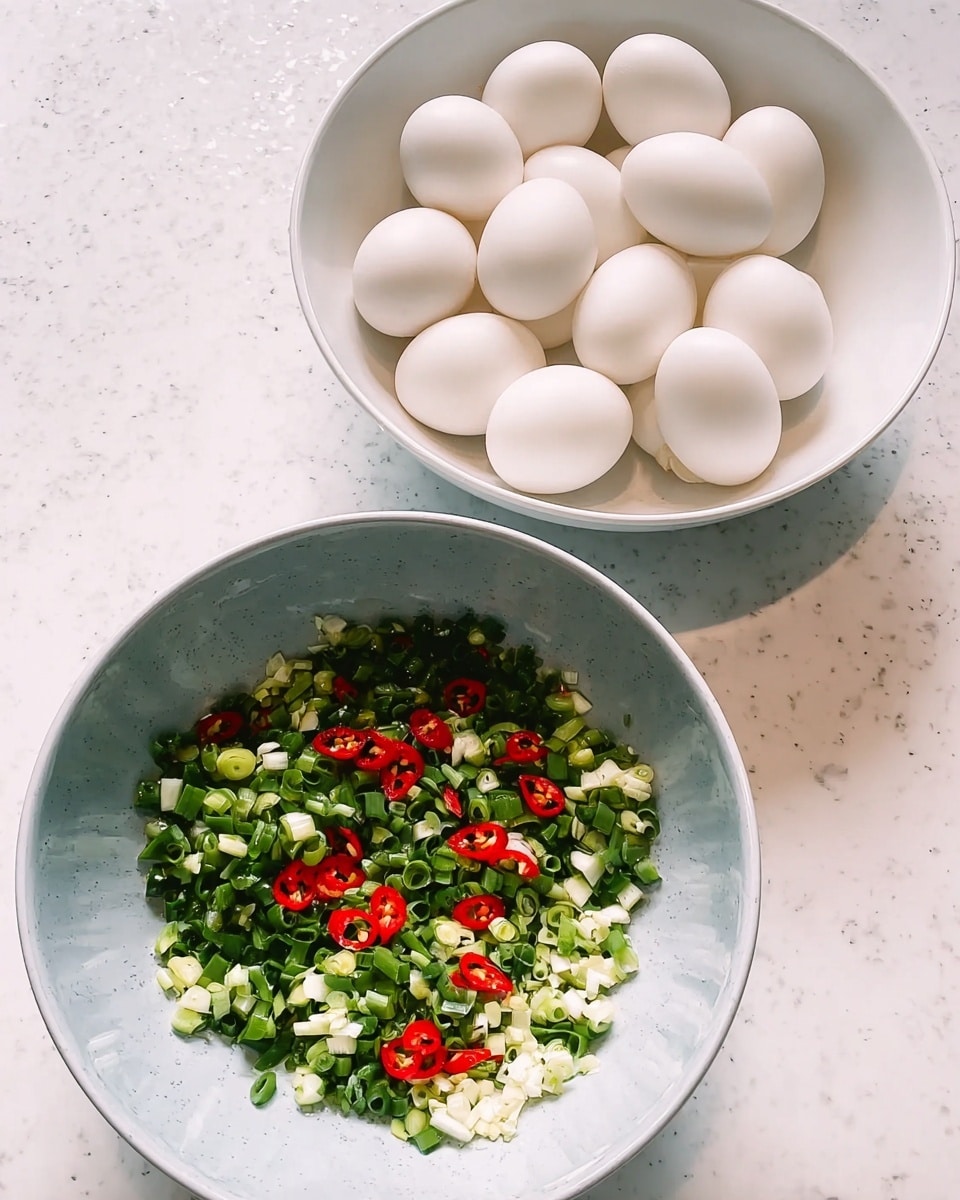 The image shows two white bowls placed on a white marbled surface. The bowl in the front contains a mixture of finely chopped green onions, white garlic pieces, and small red chili slices spread evenly throughout. The colors contrast well with the light grey inside of the bowl. In the background, the second white bowl is filled with whole white eggs, neatly placed to fill the bowl. The setup is bright and clear with a slight shadow cast beneath the bowls. Photo taken with an iphone --ar 4:5 --v 7